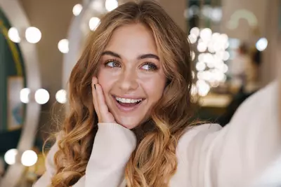 Jovem sorridente tirando selfie com cabelo com luzes