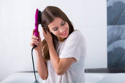 Mulher utilizando escova alisadora no cabelo