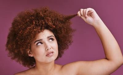 Mulher ruiva analisando seu cabelo poroso cacheado