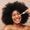 Mulher aplicando serum com peptideos de colageno no rosto com auxilio de um gotejador