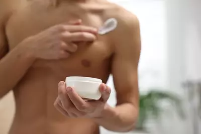 Homem passando hidratante corporal masculino no corpo