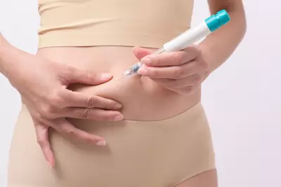 Close-up de uma pessoa aplicando uma injecao de caneta emagrecedora na regiao abdominal