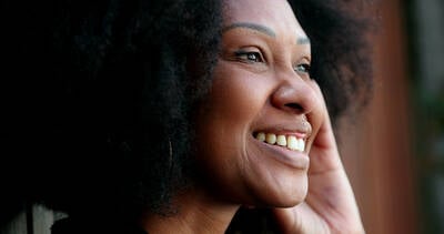 Mulher negra sorrindo e olhando para o lado