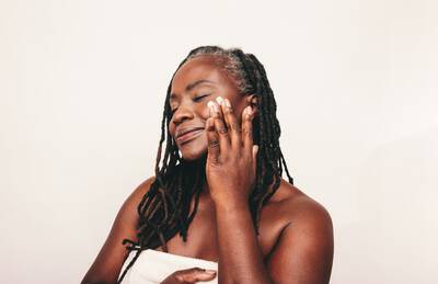 Mulher passando acido retinoico, um derivado da vitamina A usado para tratar acne, envelhecimento e manchas na pele.
