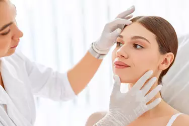 Dermatologista avaliando o rosto de mulher caucasiana