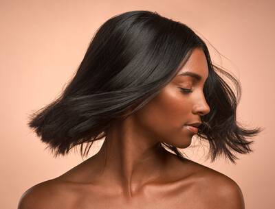 Mulher negra com cabelos lisos impecaveis apos fazer restauracao capilar