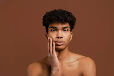 Homem negro e jovem com maos sob rosto