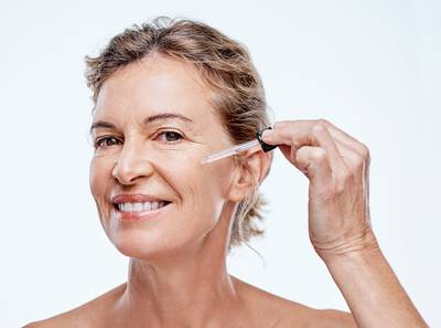 Mulher madura passando serum facial clareador no rosto