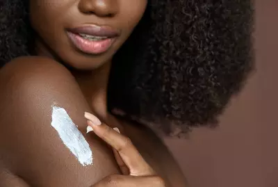 Mulher aplicando produto com ceramidas na pele negra