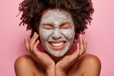 Mulher aplicando mascara facial de argila verde para limpar e equilibrar a pele.