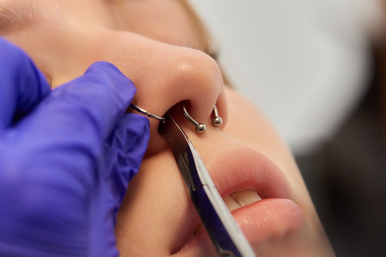 pessoa aplicando piercing no nariz