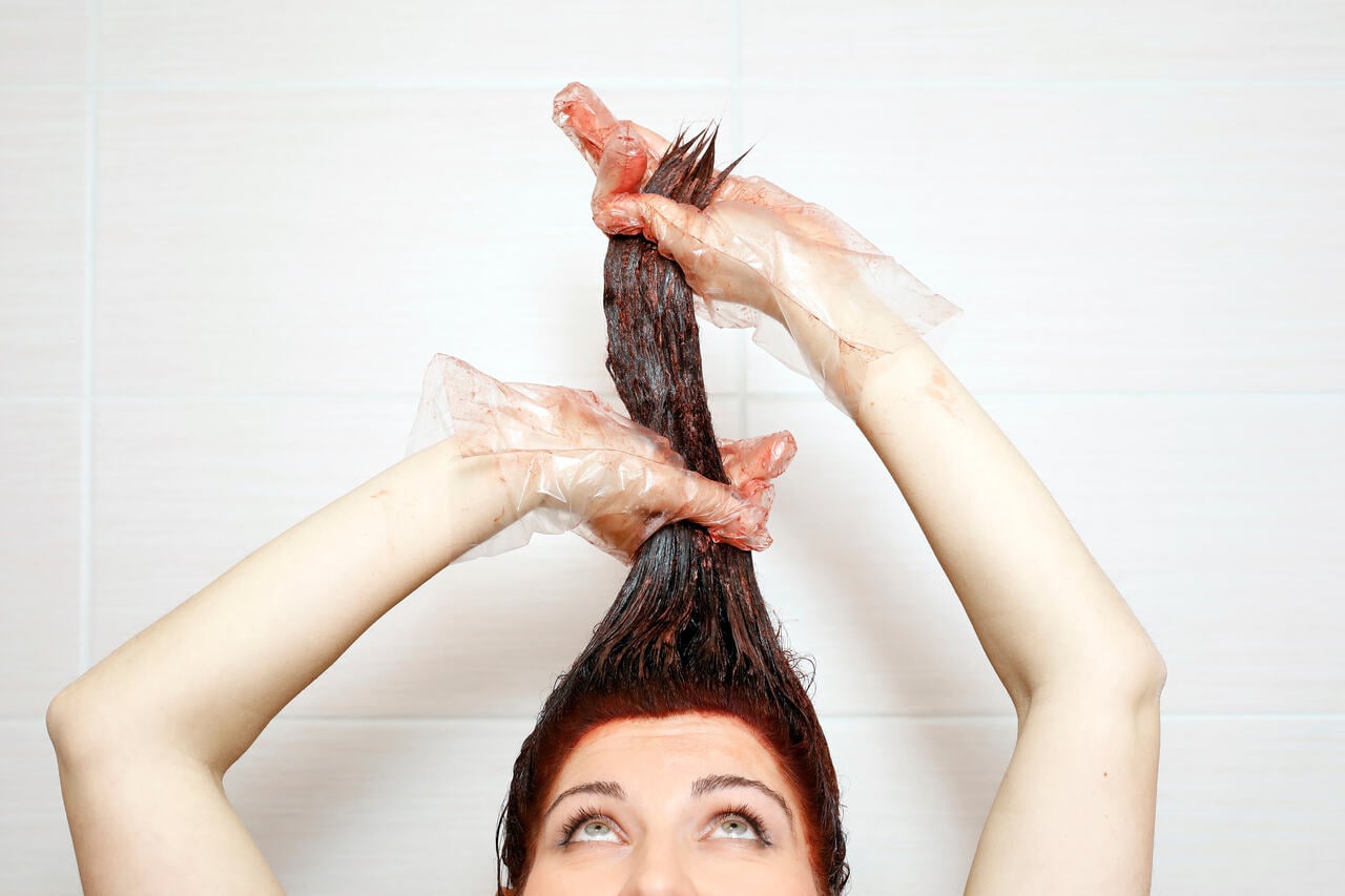 Mulher pintando o cabelo em casa e manchando a pele