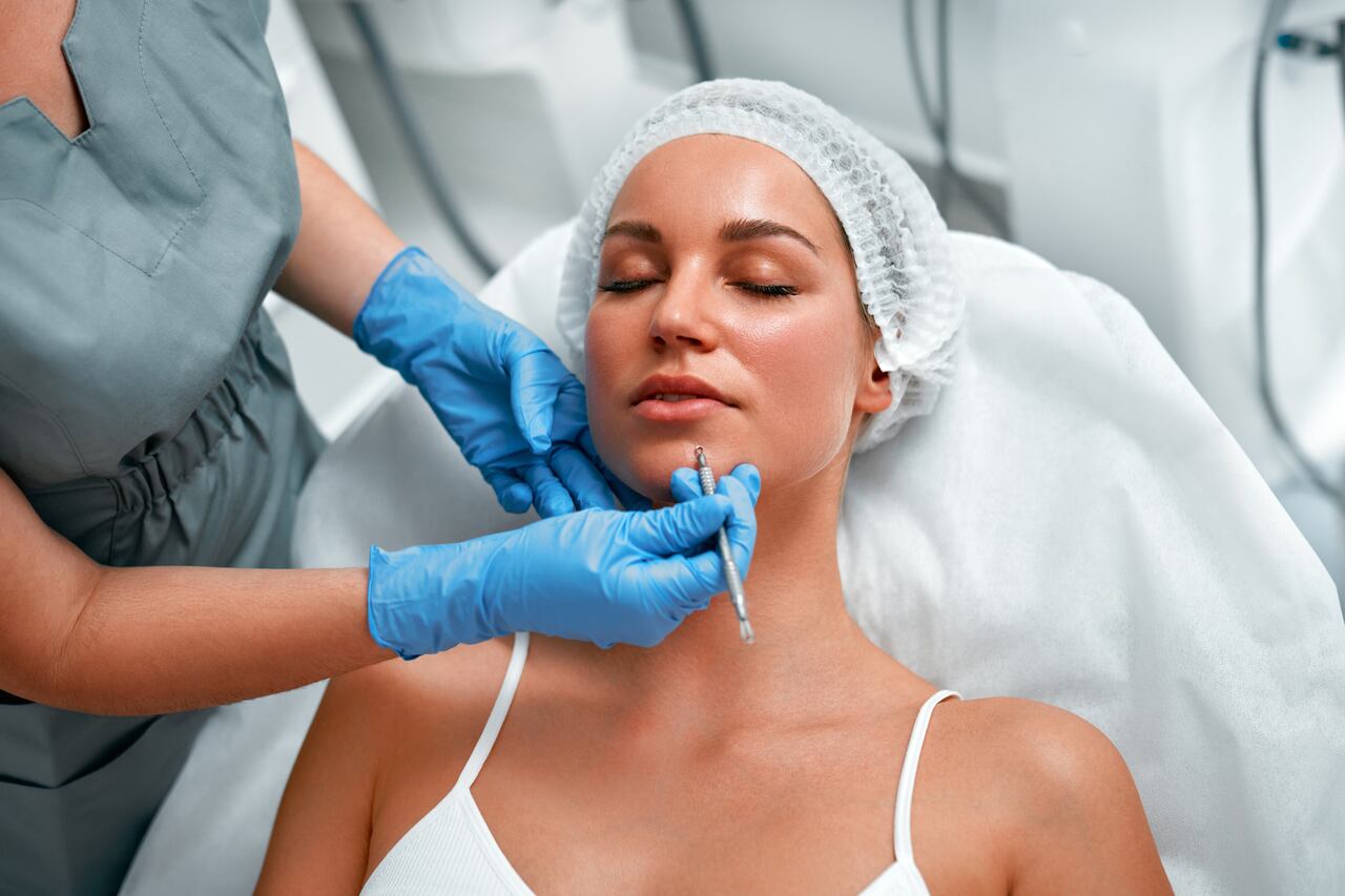 Profissional fazendo limpeza de pele em mulher de olhos fechados