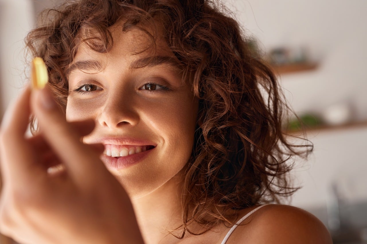 Cápsula de vitamina c lipossomal em uma mão de uma mulher jovem