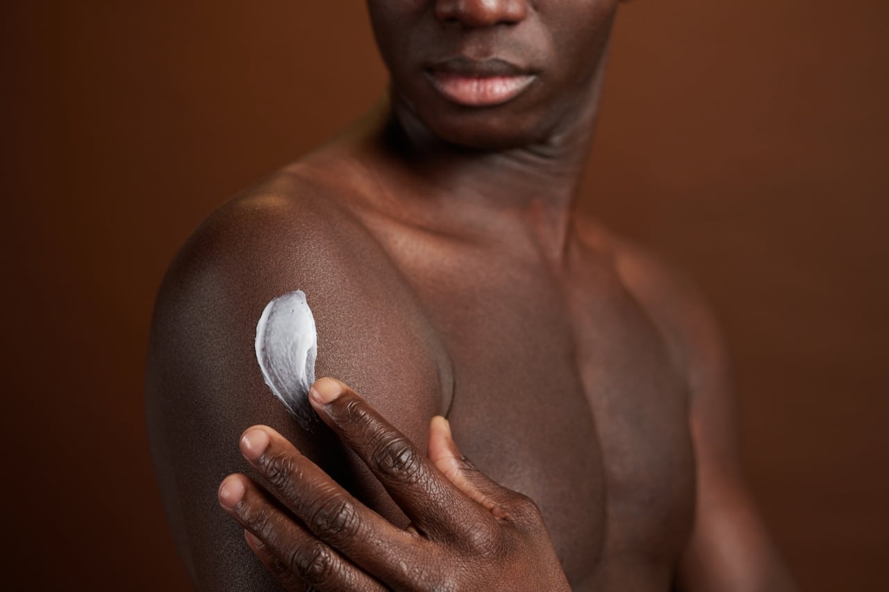 Homem aplicando produto com ceramidas na pele negra