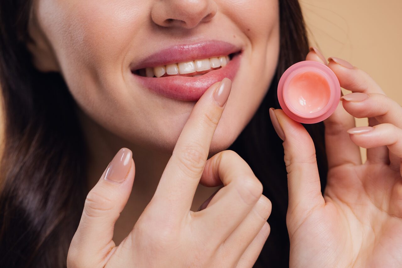 Mulher usando lipbalm rosado nos lábios