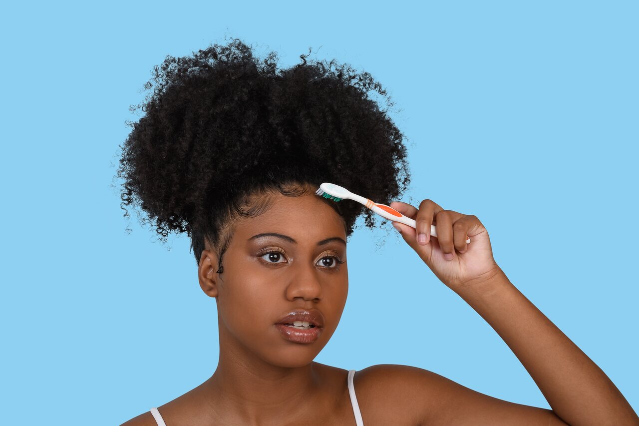 Mulher fazendo baby hair no cabelo com escova de dente